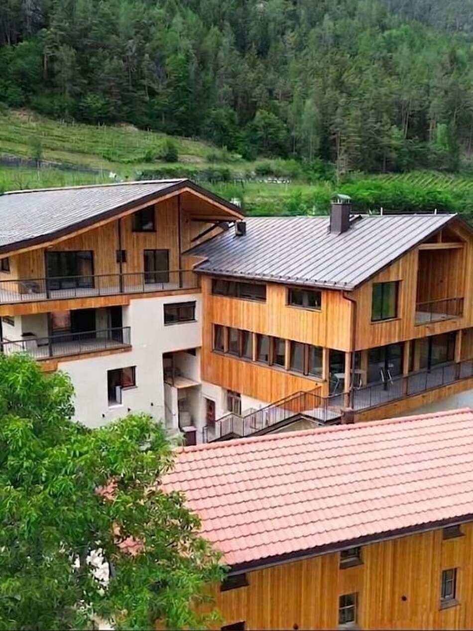 Bio-Weingut Santer in Mühlbach, Südtirol Bio-Weingut Santer mit Holzgebäuden inmitten von Weinbergen in Mühlbach, Südtirol, umgeben von grüner Natur.